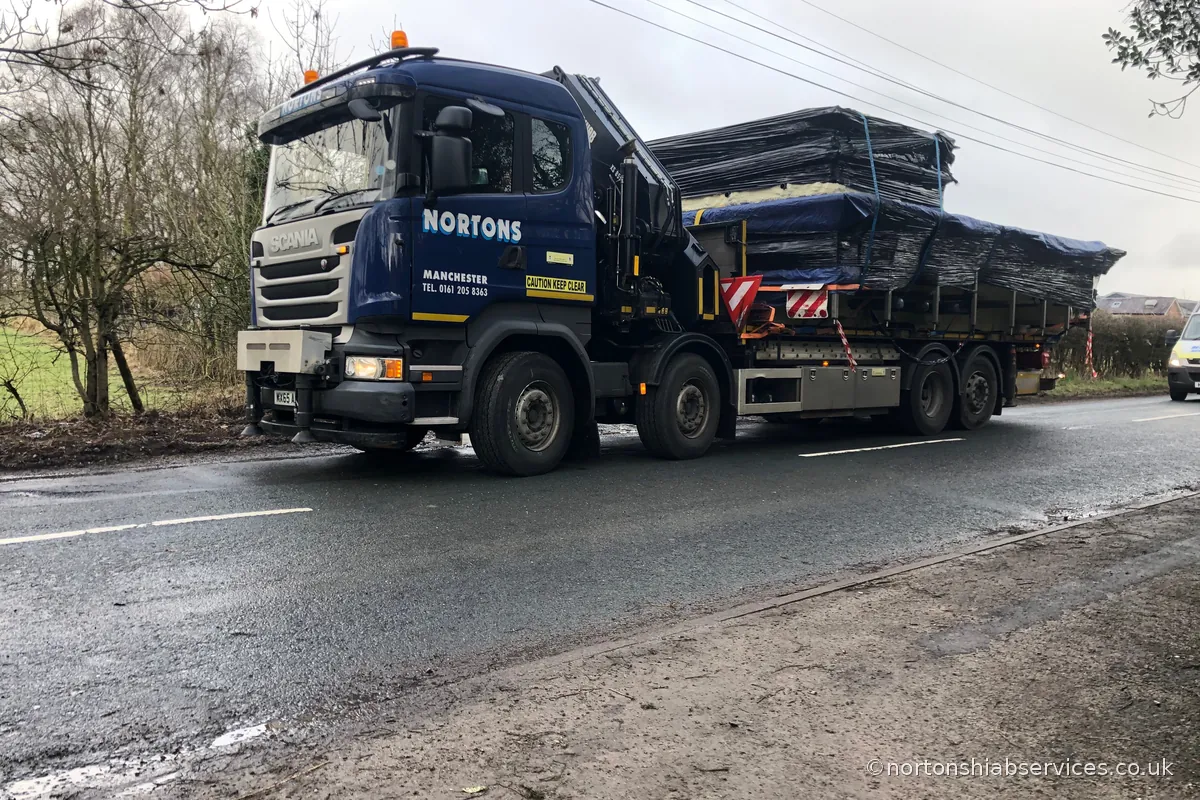 A Nortons crane lorry carrying a 14ft wide medical pool as a wide load on the road into Wigan