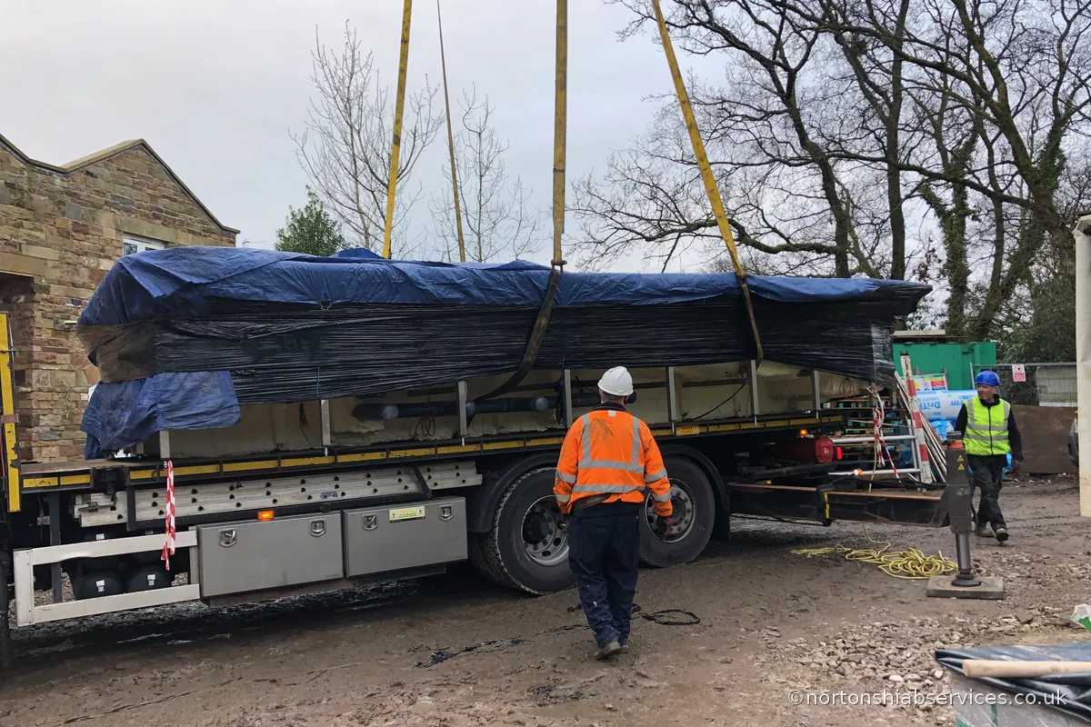 A Nortons driver / operator alongside the crane lorry with the medical pool rigged on four slings ready to lift at Wigan