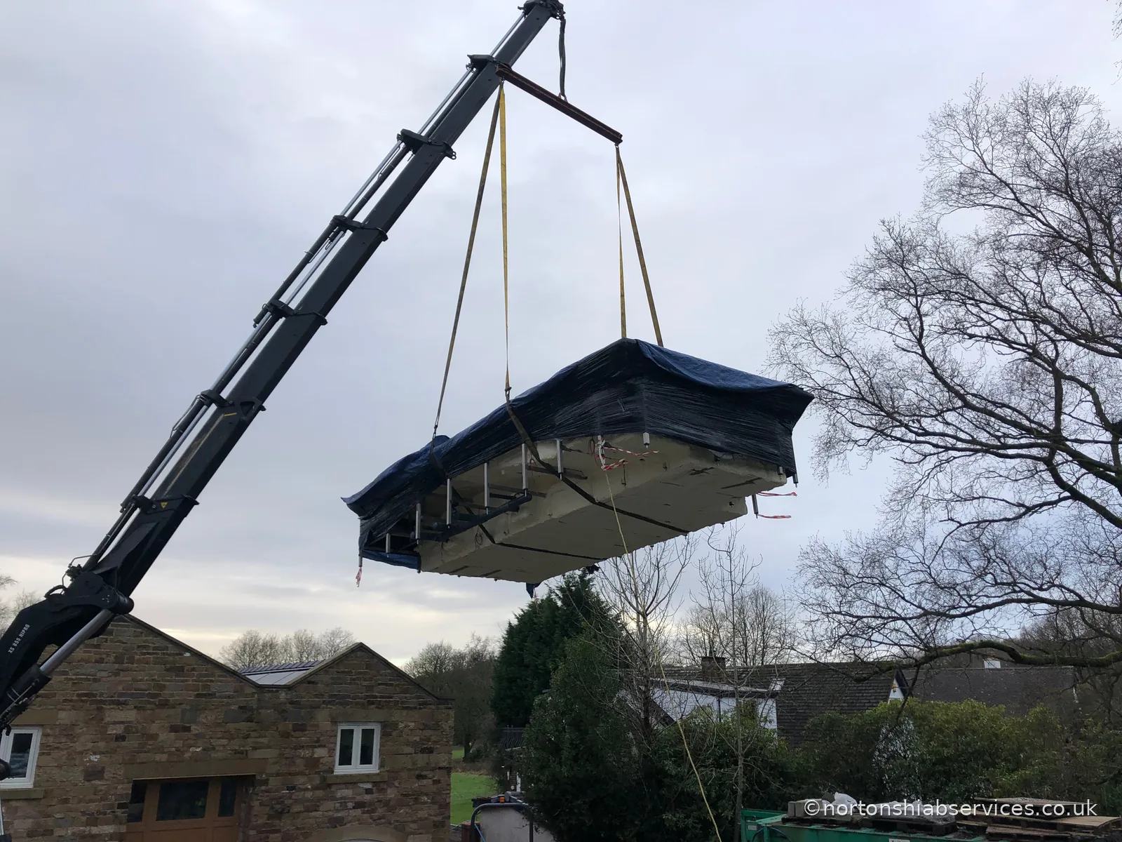 A Nortons 855 hiab holding a 14ft wide medical pool level and clear in the air on a new build at Wigan