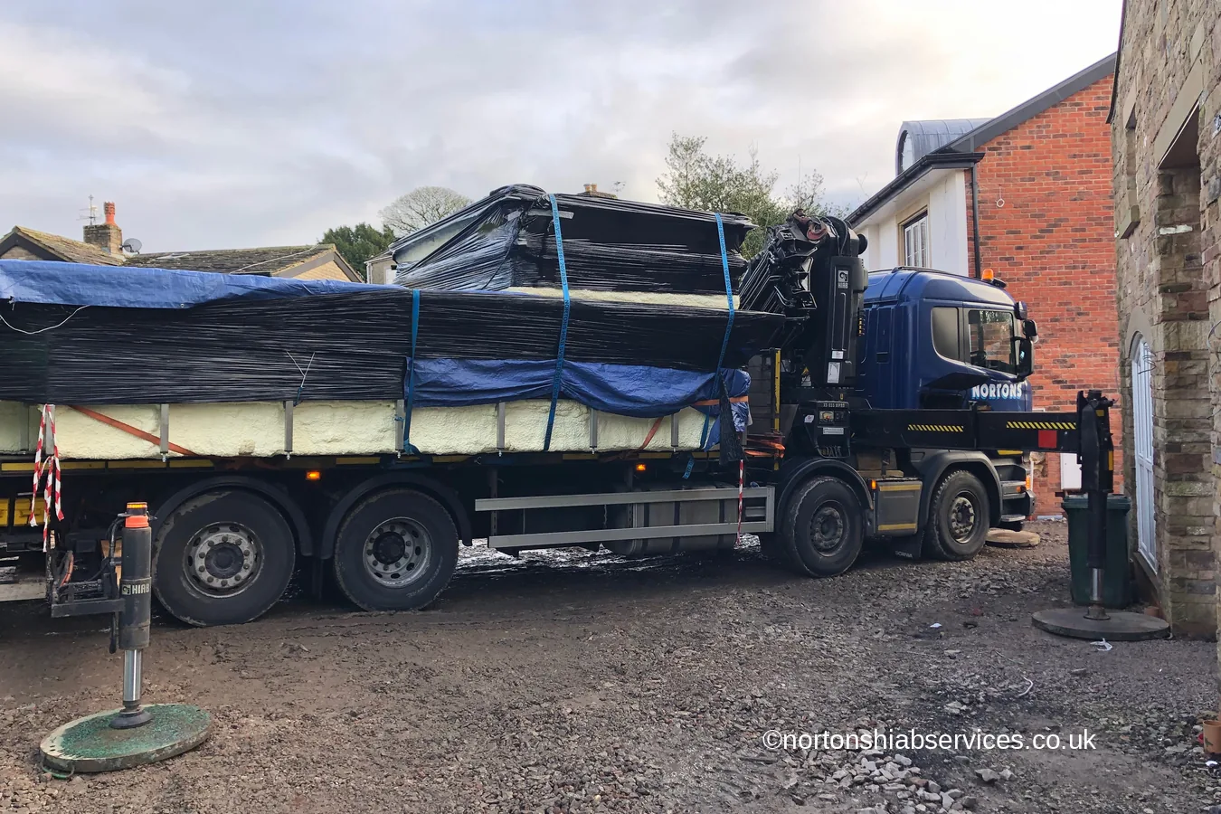 The 14ft wide medical pool sheeted and strapped on the bed of a Nortons crane lorry standing at the new build at Wigan