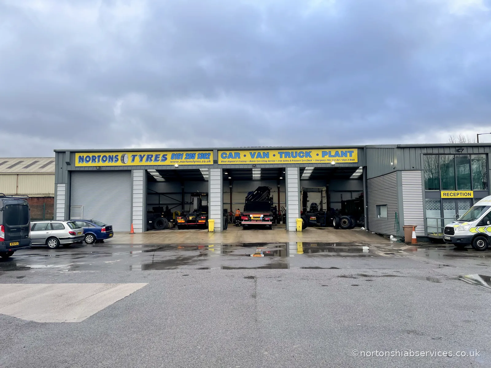The Nortons Tyres depot with three open bays, vehicles inside and the mobile van parked outside