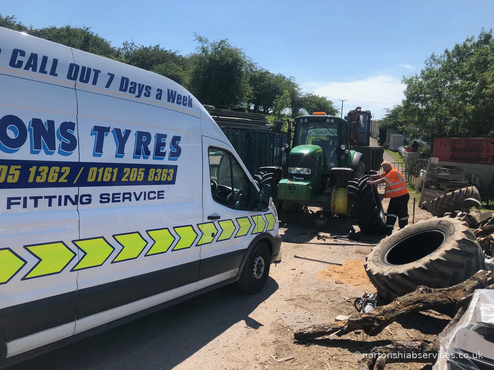 A Nortons Tyres mobile fitting van on site beside a tractor with a wheel off and a fitter working on it