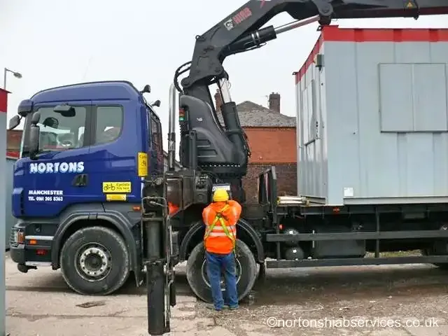 Nortons driver / operator at the crane controls of an eight-wheel rigid hiab with a cabin on the bed