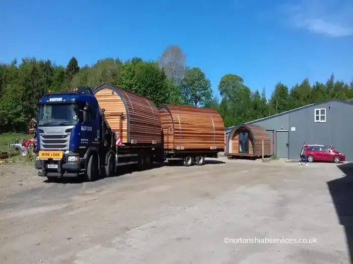 Nortons hiab lorry and drag trailer loaded with two timber-clad pods