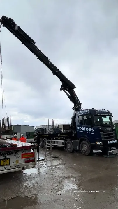 Nortons Scania 858 with the crane raised on a wet yard, a loaded trailer alongside