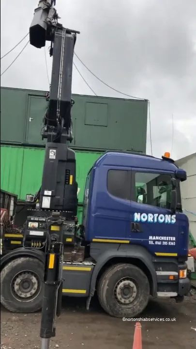 Nortons Scania with the crane up beside a green anti vandal cabin
