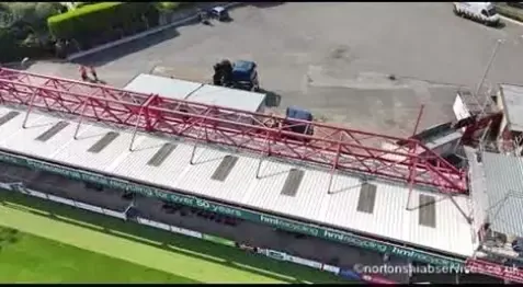 Nortons vehicles being prepared beside the red stand at a football ground