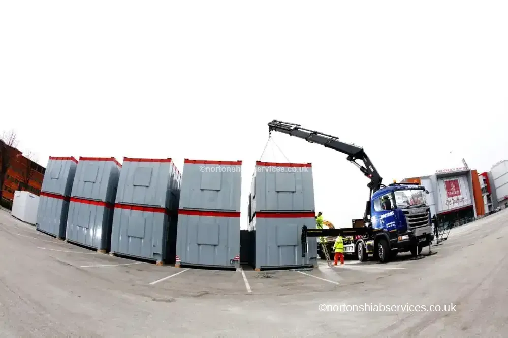 A Nortons crane placing a grey site cabin precisely onto a stack of cabins